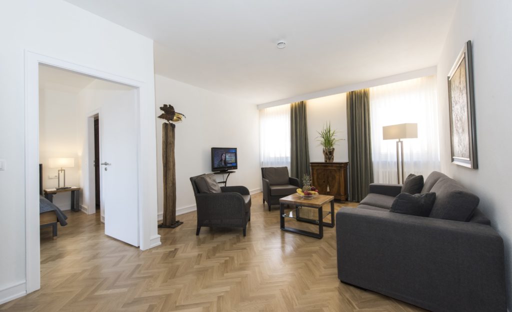 Geräumiges Appartment mit Sitzecke, Doppelbett und Fernseher im Hotel Goldener Engel Speyer
